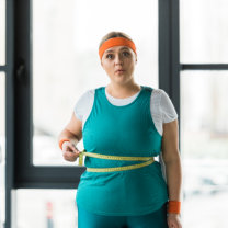 Woman measuring waist with tape at the gym
