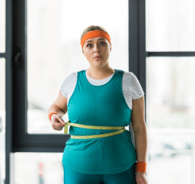 Woman measuring waist with tape at the gym