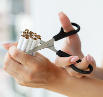 Hands cutting cigarettes with scissors