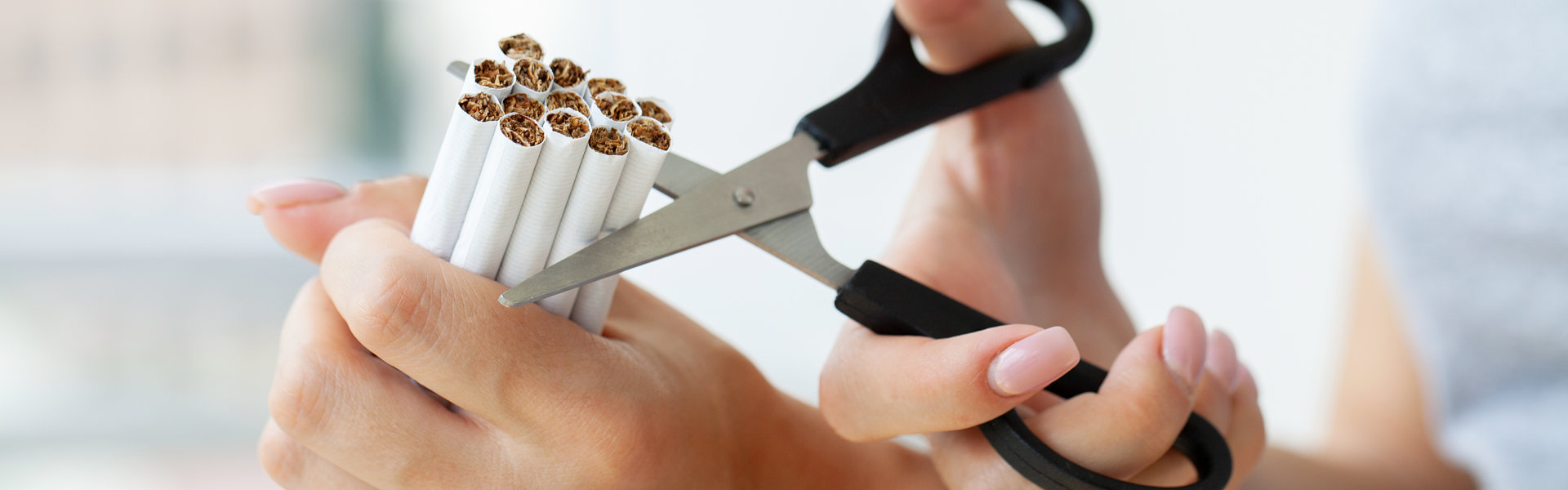 Hands cutting cigarettes with scissors