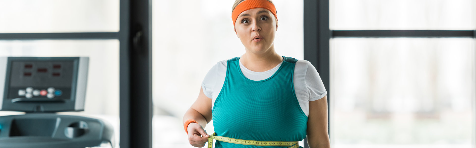 Woman measuring waist with tape at the gym